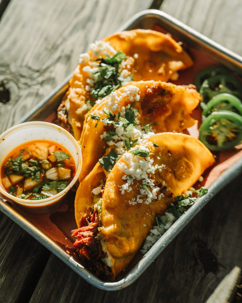 Brisket birria tacos with consommé, cilantro and onion
